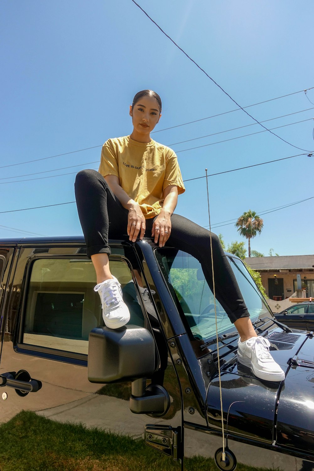 woman in yellow crew-neck T-shirt sitting on top of car