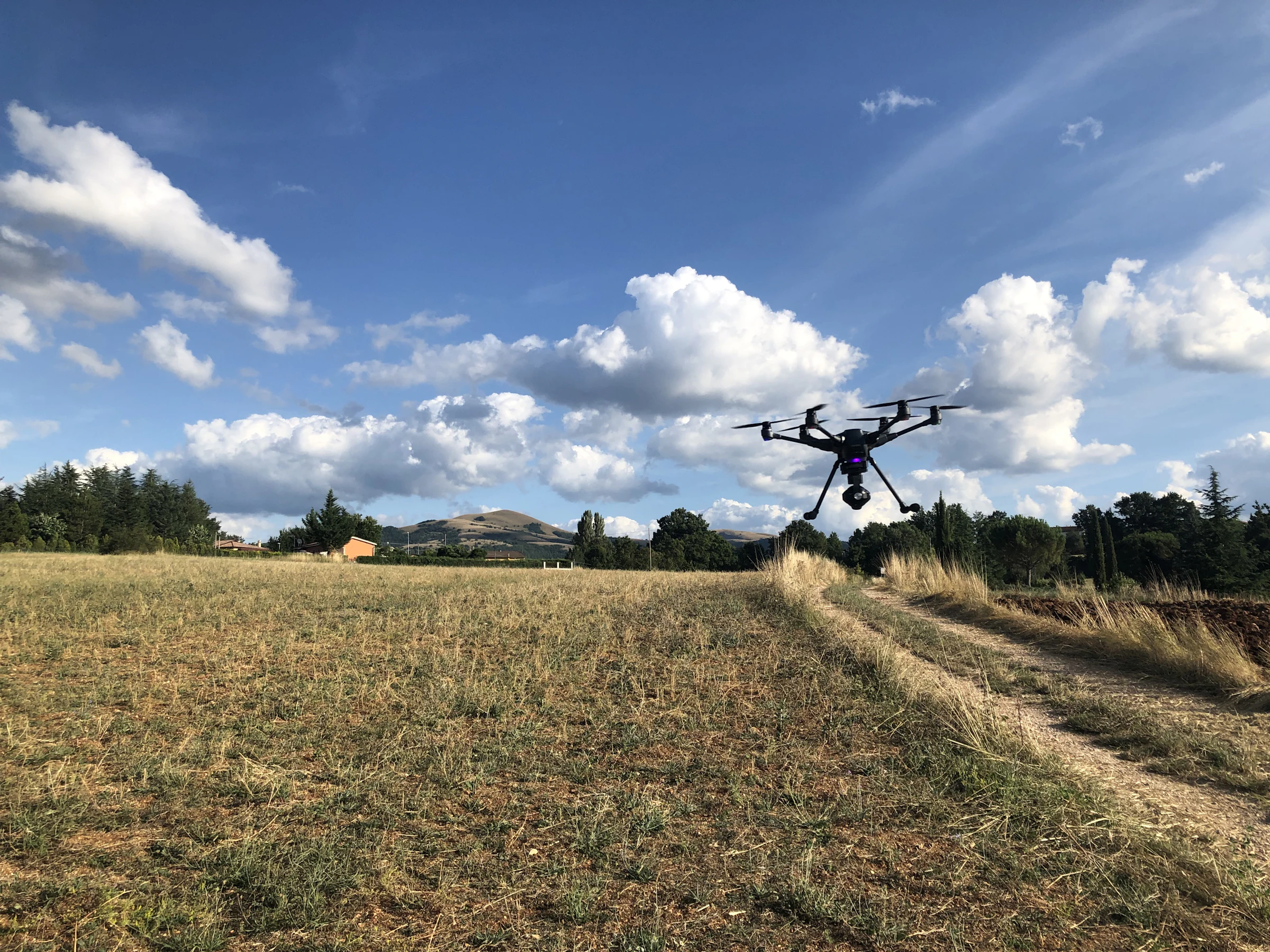 Drone hovering over a green rural field