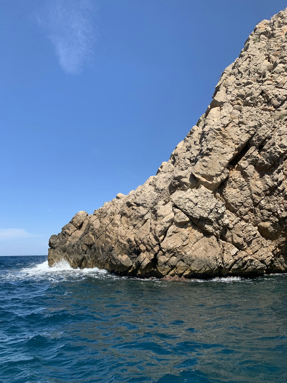 rocky hill viewing blue sea during daytime