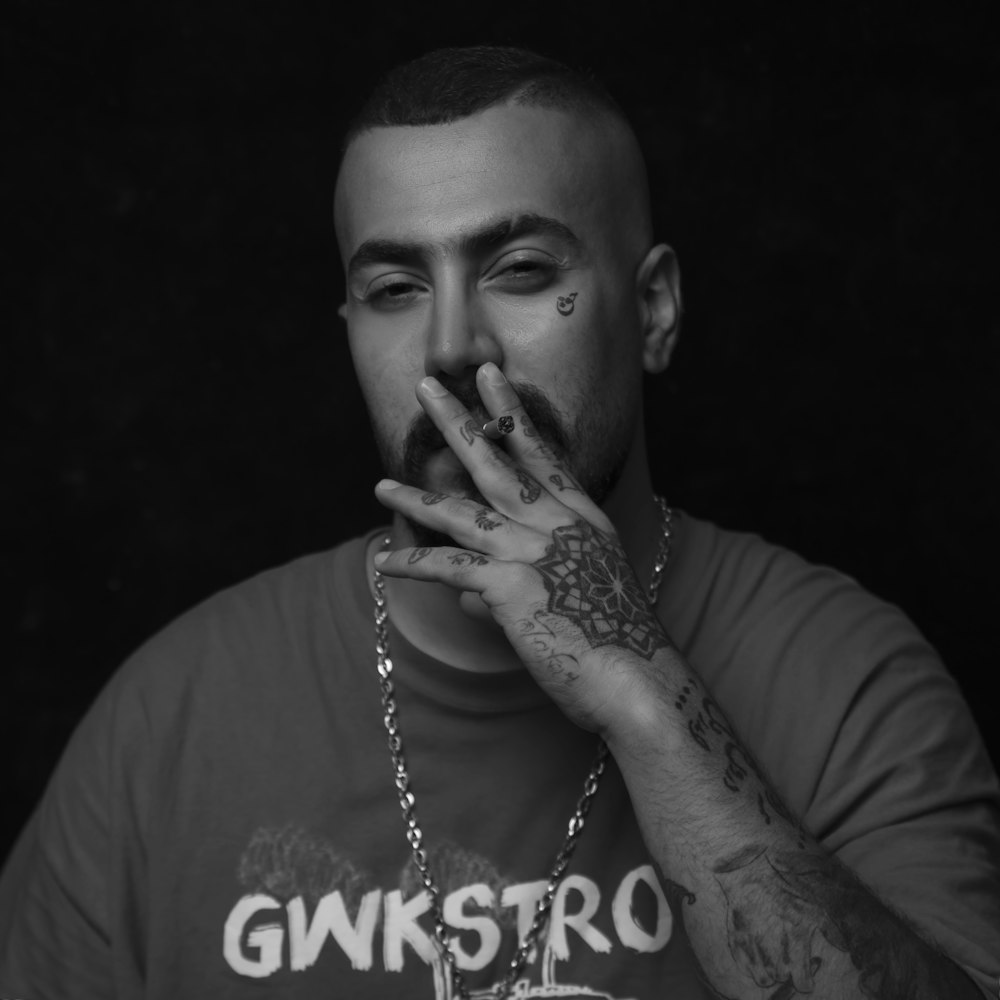 man smoking wearing necklace and printed shirt