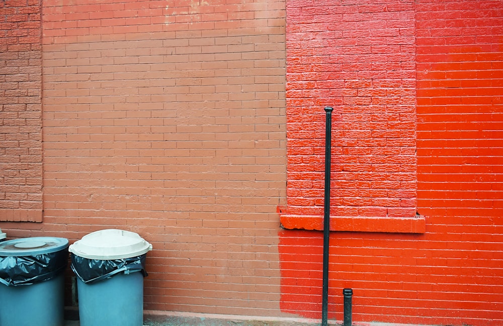 two blue plastic water drums beside concrete wall