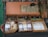 A display of various Italian specialty products, including packaged pasta and bottles of liqueur, arranged in wooden crates and a basket. A hand-painted sign reading 'Specialità D'Ischia' is placed prominently above the products. The setup suggests an artisanal or rustic market ambiance, with some greenery and wooden elements adding to the aesthetic.