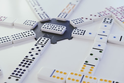 Illustration showing domino pieces in various game positions with mathematical symbols overlay.