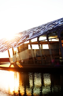Sunlight reflecting off the glass facade of a high-end home nestled by the water.