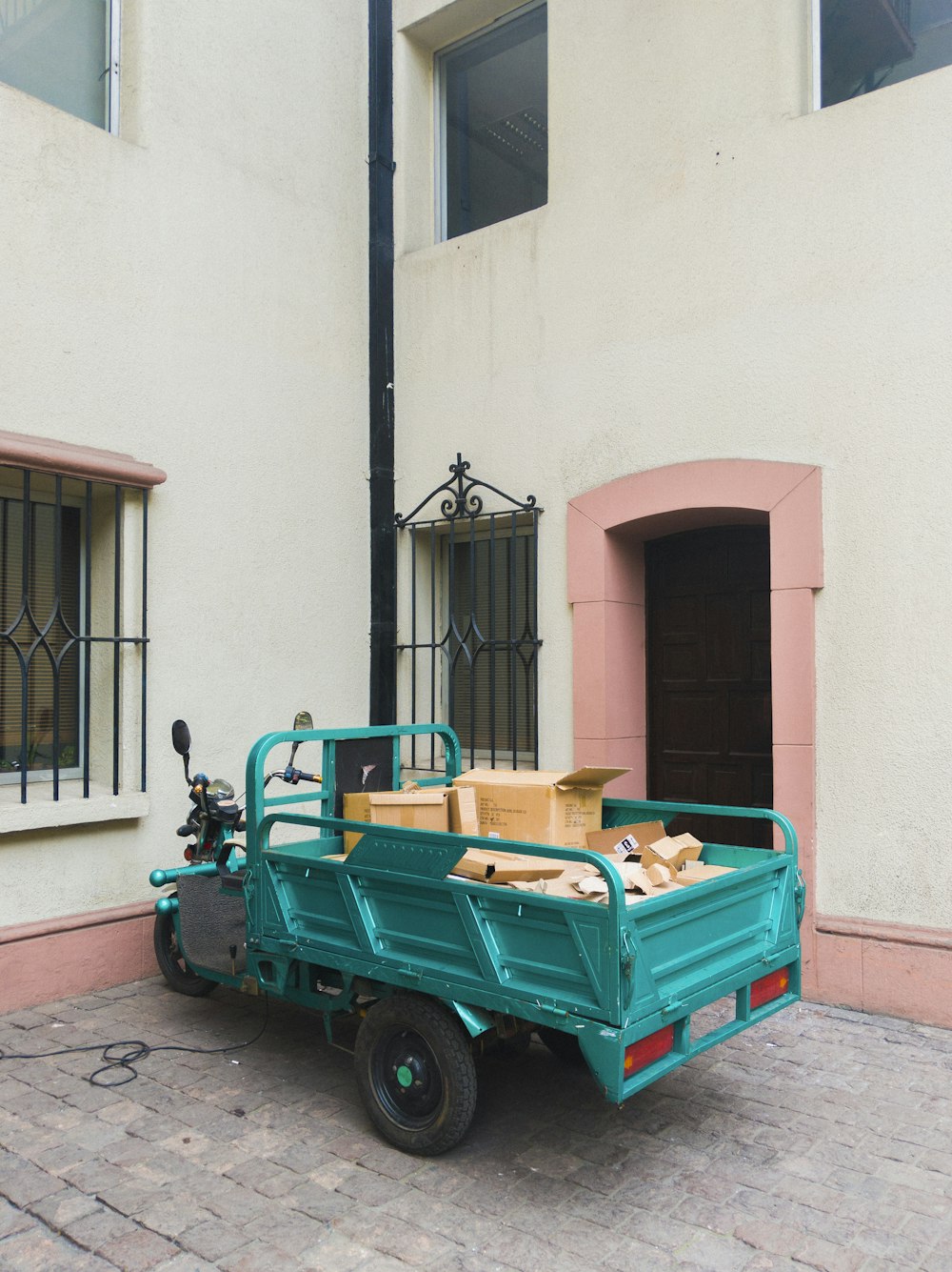 teal 3-wheeled cargo vehicle park near apartment complex