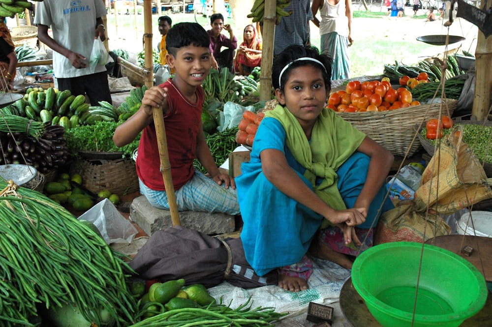 menina e menino sentados entre legumes