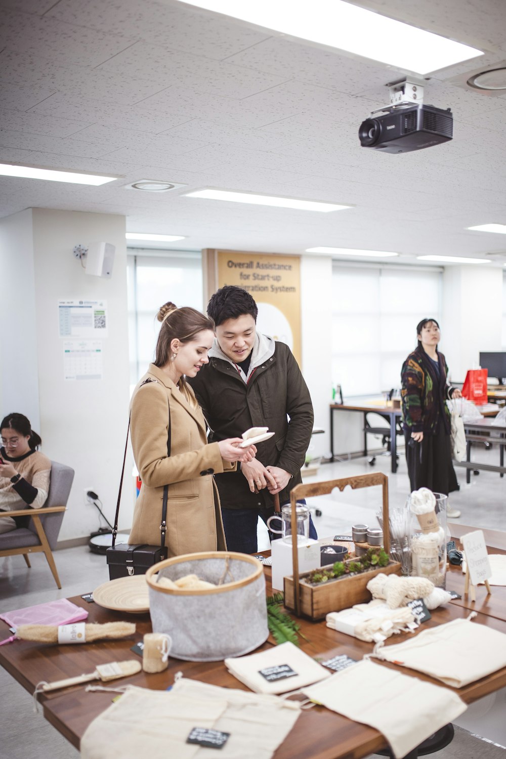 people standing and sitting inside building with tables and chairs