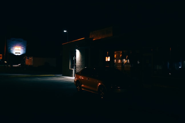 A quiet city street at night with a private car waiting for pickup.