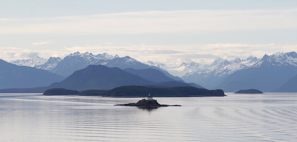 lighthouse on isle near mountains during day