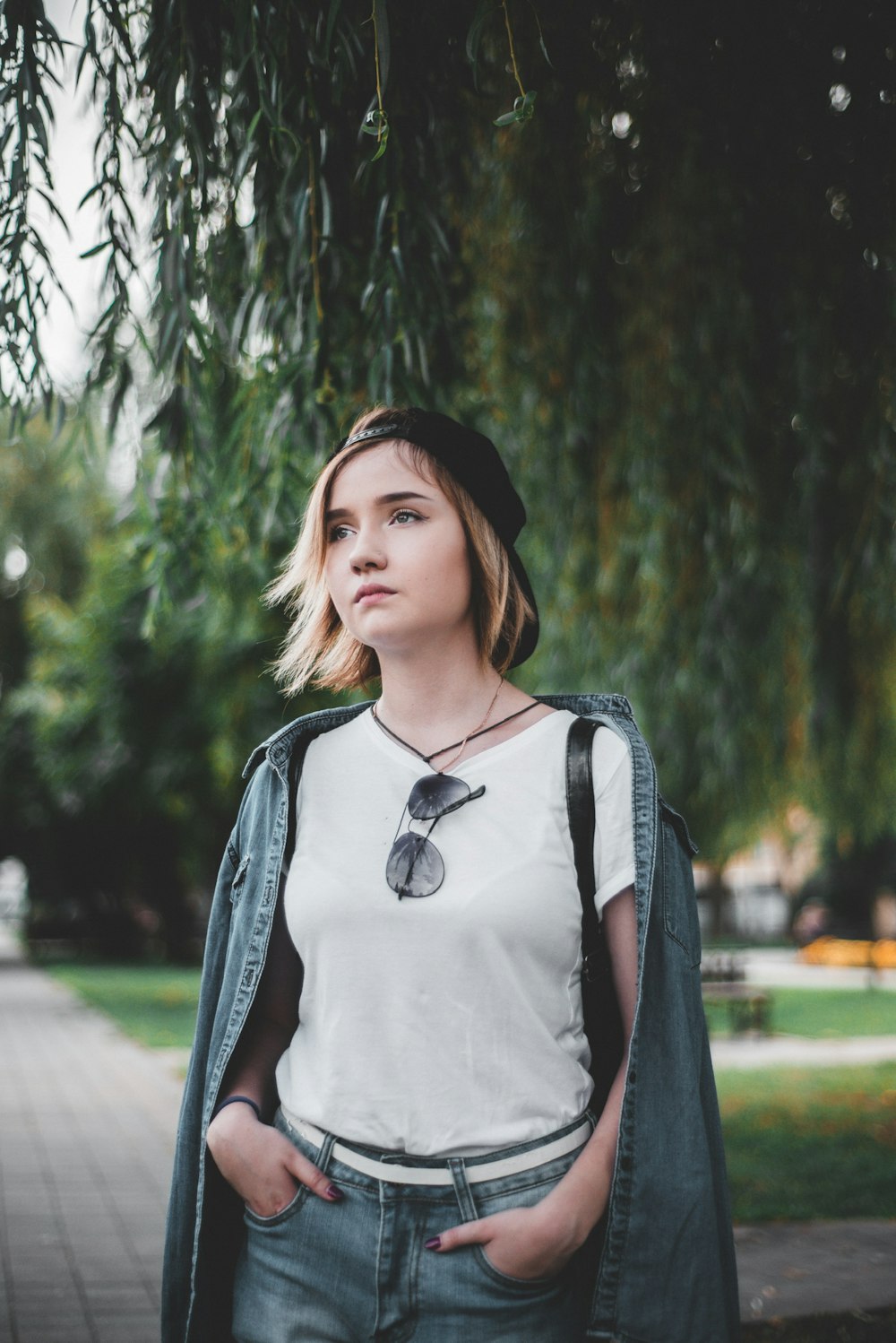 woman standing with both hands in her bottoms's pockets near tree