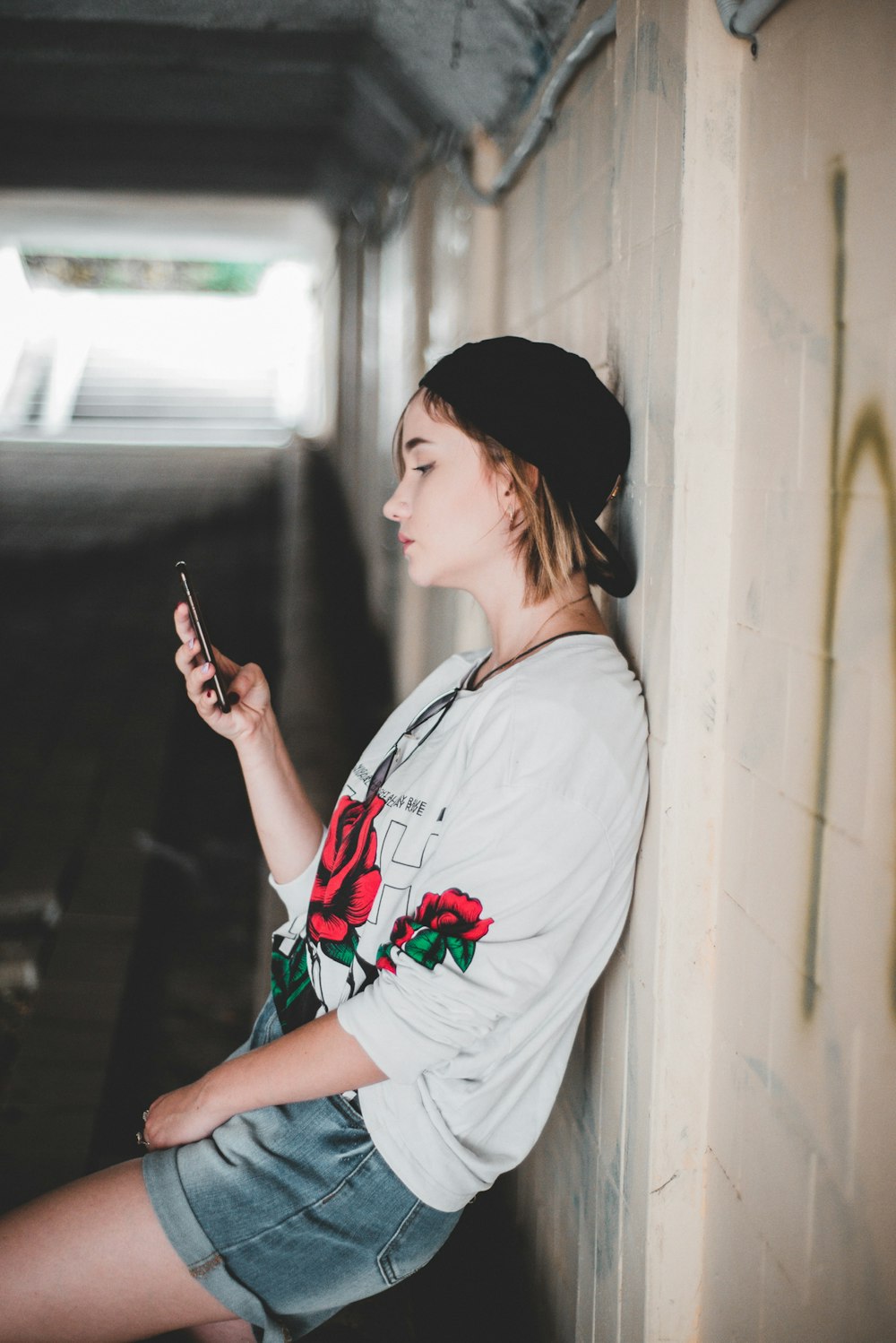 woman leaning on wall using smartphone