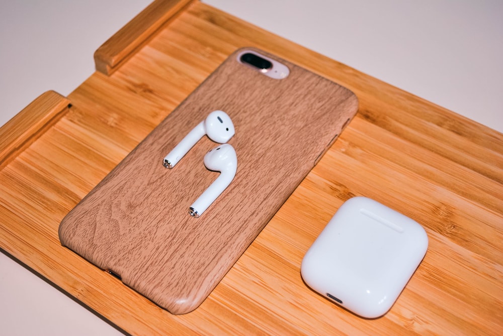 Apple AirPods with charging case on brown chopping board