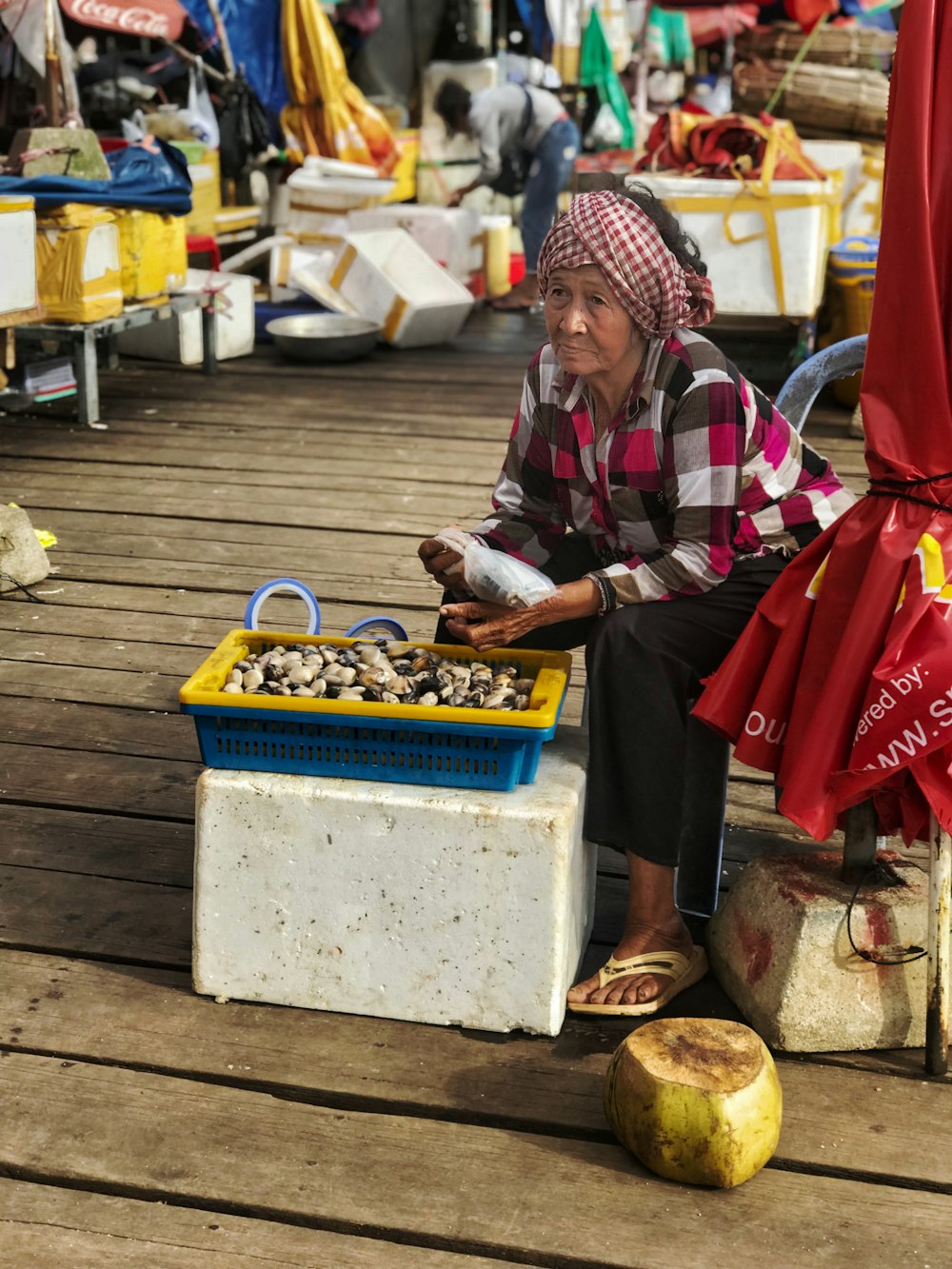 woman sitting beside plastic tray of vegetable