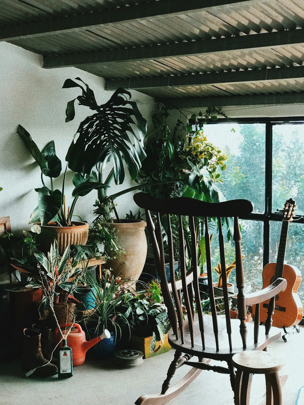 brown wooden rocking armchair facing classic guitar