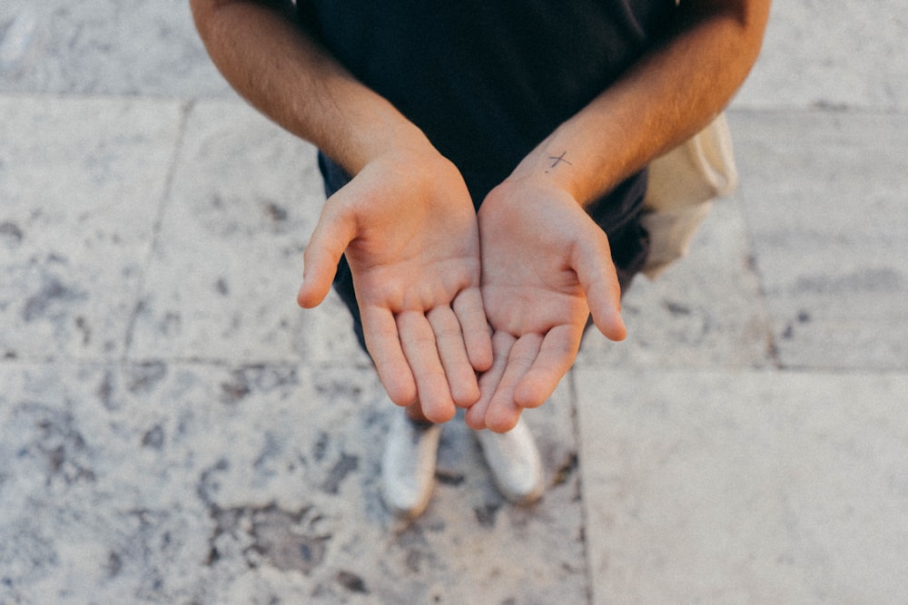 a person sitting on the ground holding their hands together