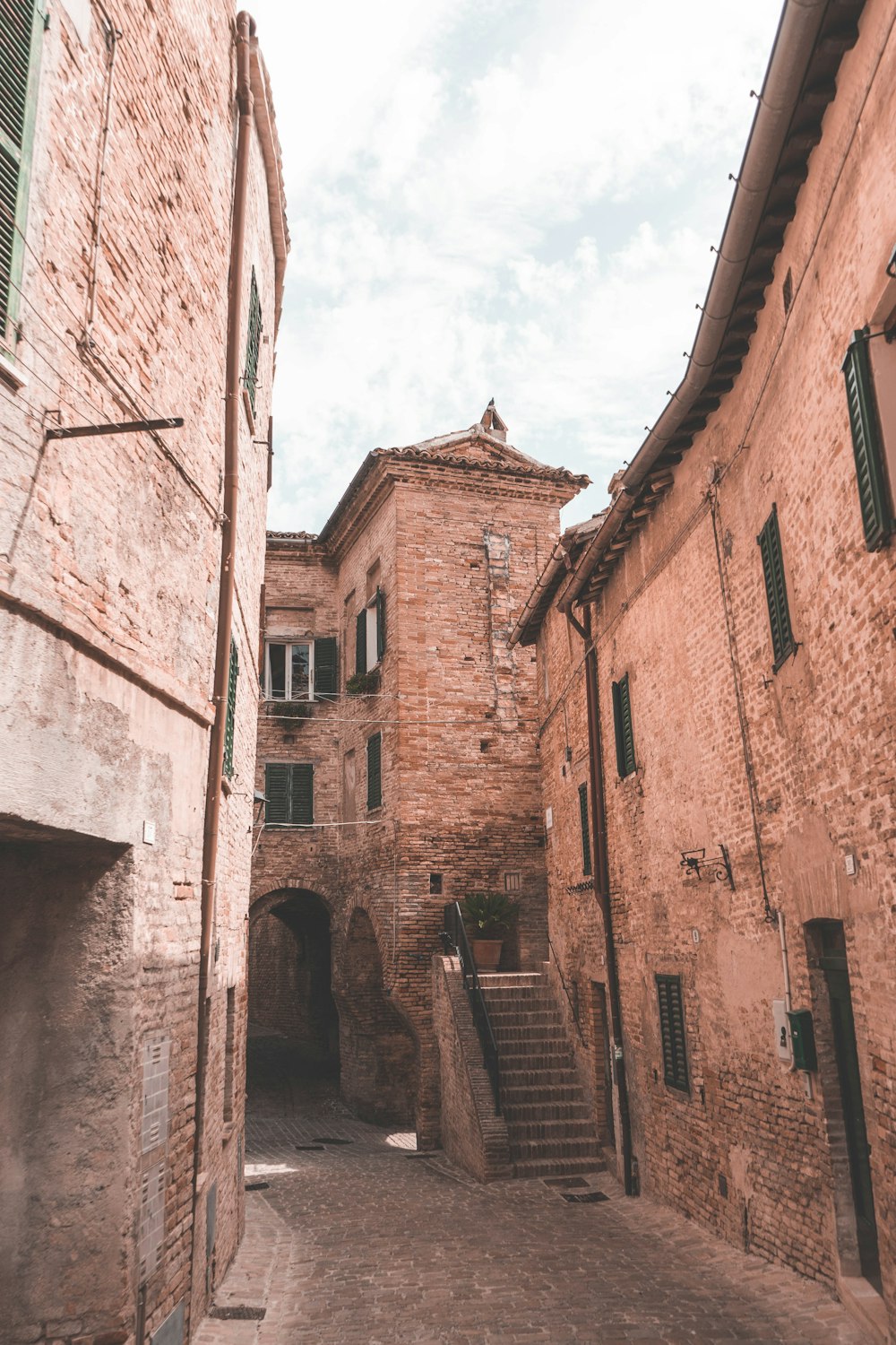 a narrow alley way with stone buildings and green shutters