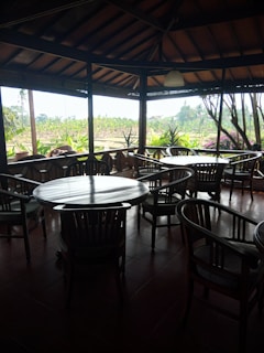 A cozy dining area with wooden tables and green plants, inviting guests to relax.