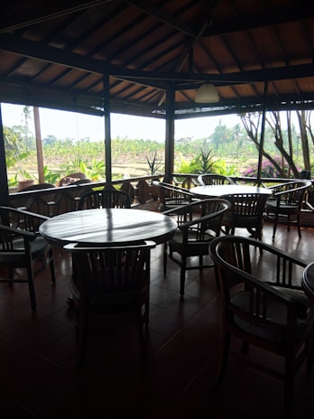 A cozy dining area with wooden tables and green plants, inviting guests to relax.