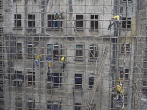 Workers assembling scaffolding on a building facade.