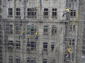 Workers performing concrete and carpentry repairs on a commercial property exterior.