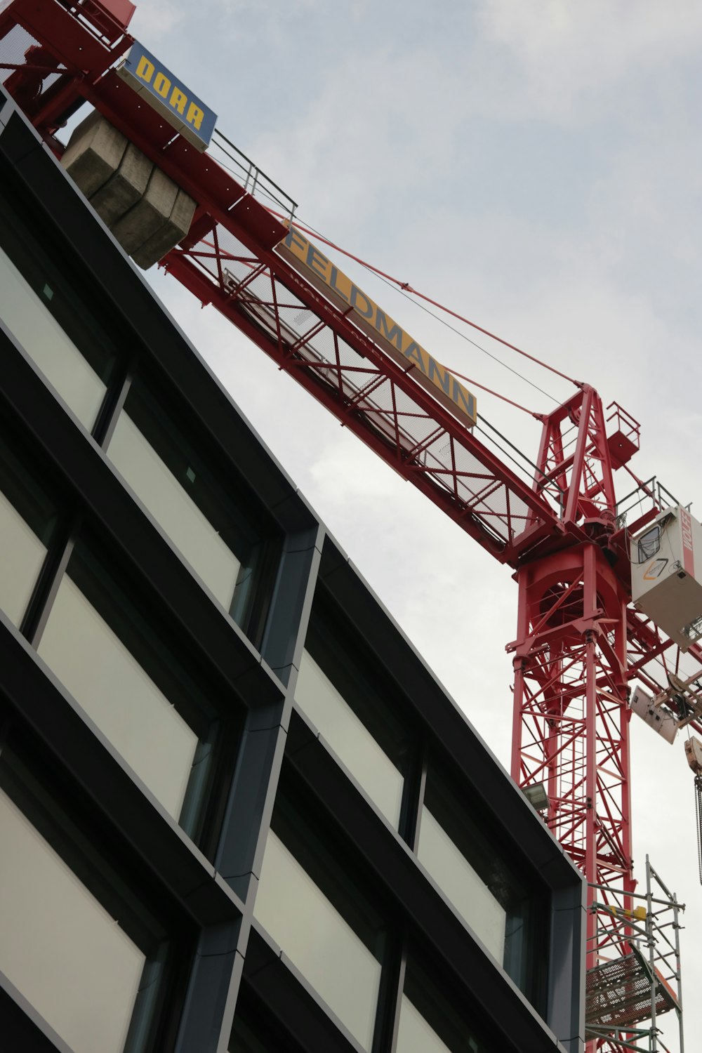 red metal crane above gray building