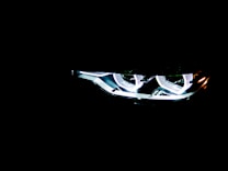 Brightly illuminated LED headlights with a modern, sleek design visible in the darkness, emphasizing a futuristic and high-tech aesthetic.