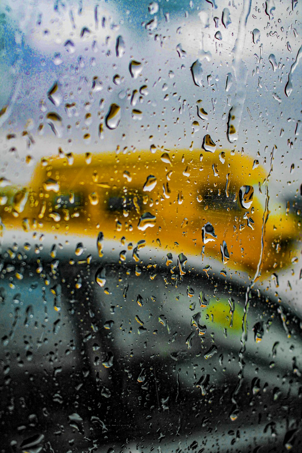 a rain covered window with a school bus in the background