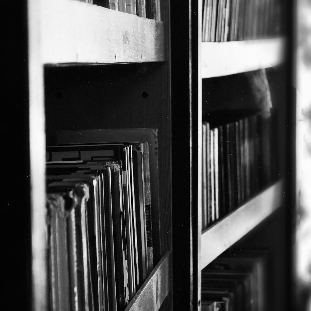 grayscale photography of books on bookcase