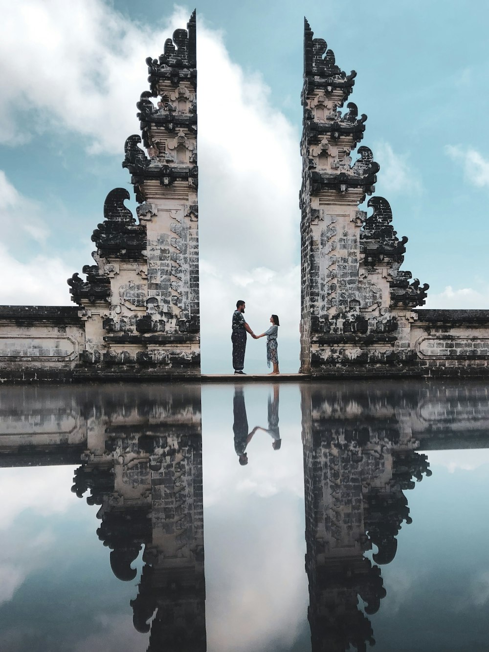 two people standing near calm body of water