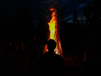 A glowing bonfire surrounded by drummers and attendees under the night sky.