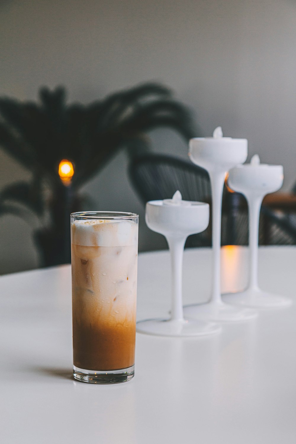 full drinking glass beside white footed glasses