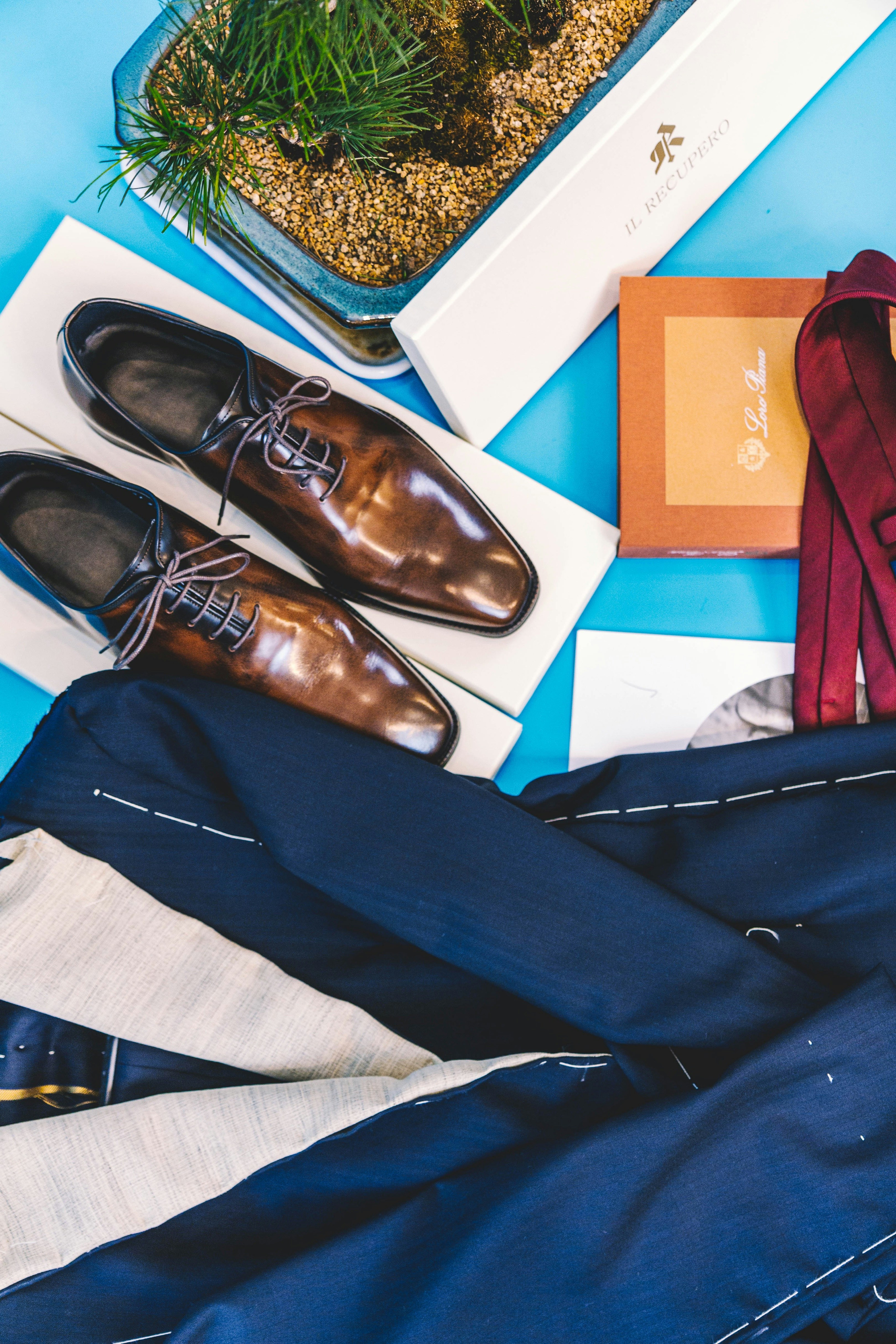 pair of brown leather dress shoes beside blue suit jacket
