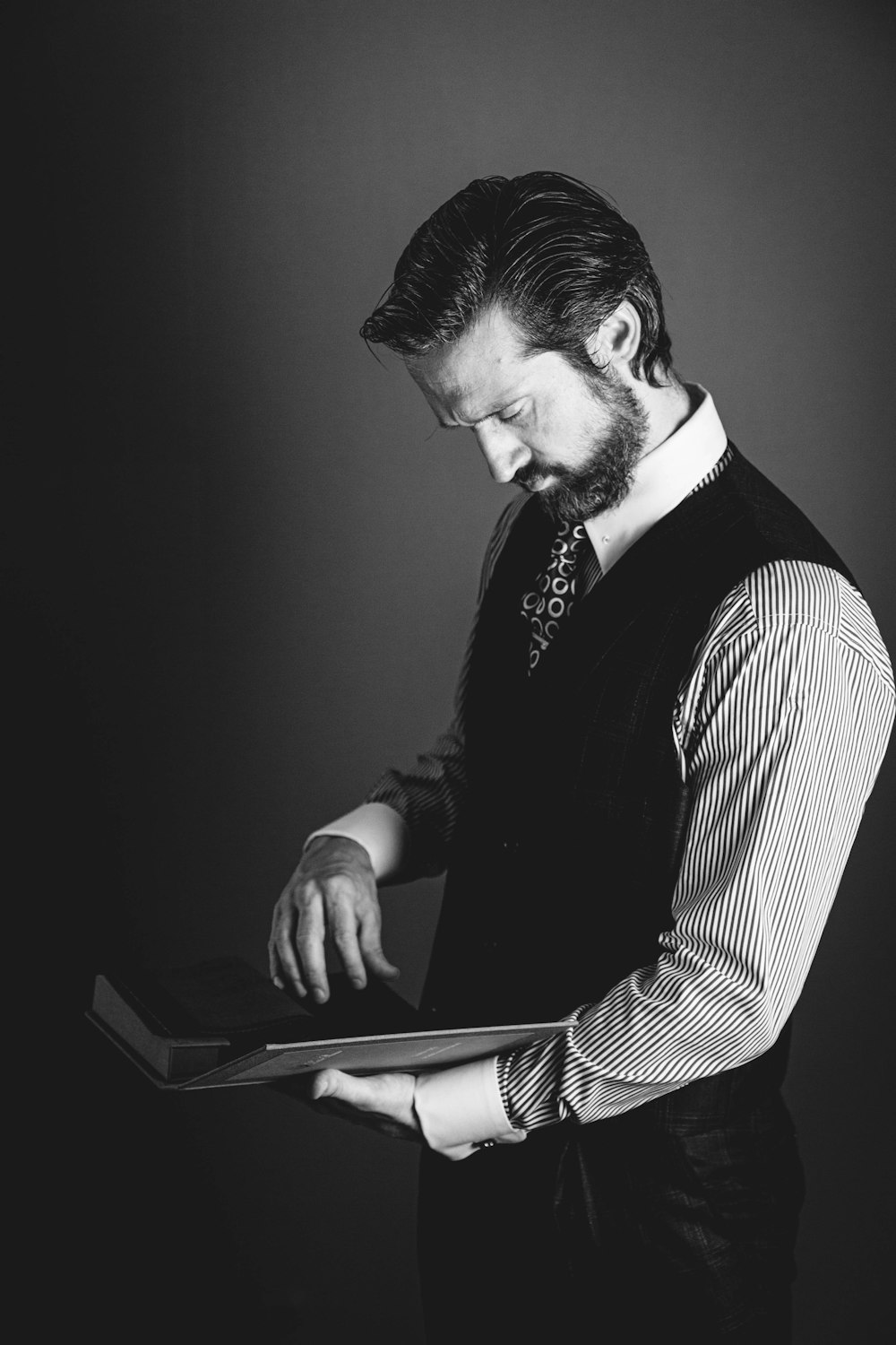 man reading book while standing inside room