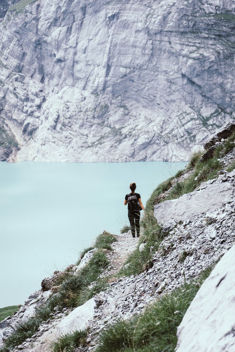 person standing on cliff near lake during daytime
