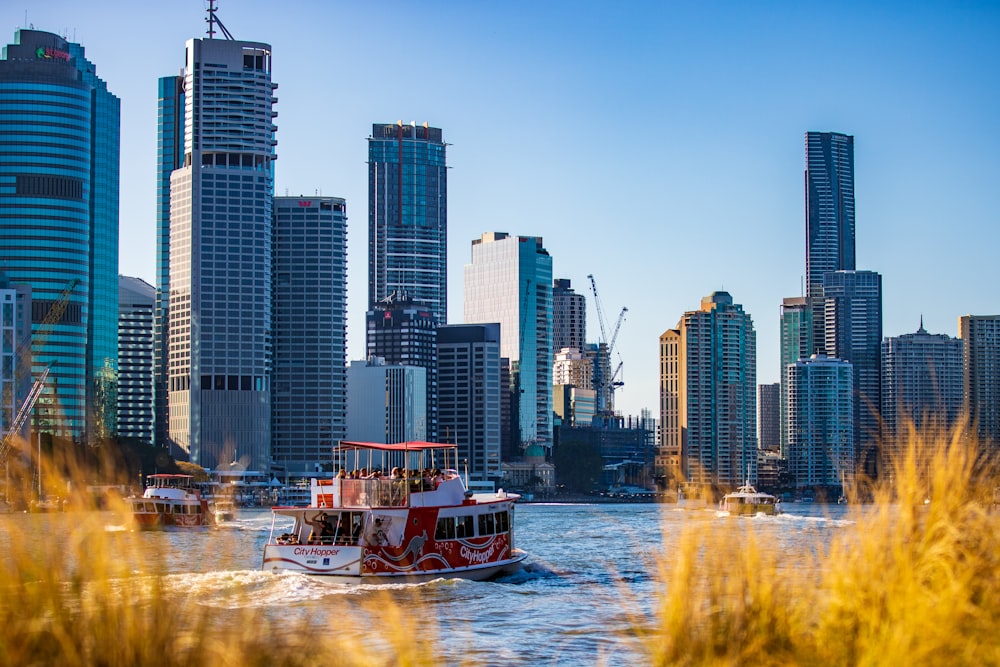 boat sailing near city skyline under clear blue sky during daytime