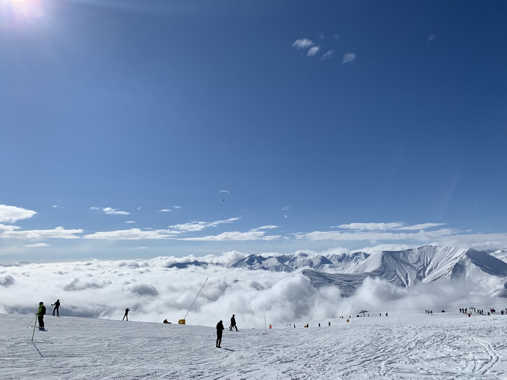 personnes dans un champ enneigé sous un ciel bleu et blanc pendant la journée