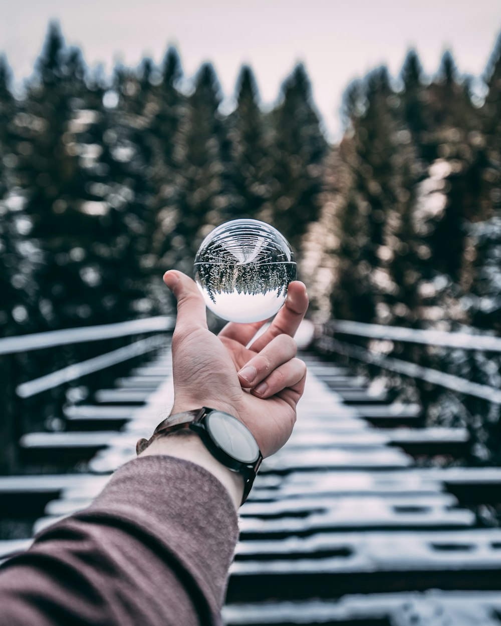 person holding glass ball standing on bridge