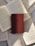 A hardcover book with a maroon cover rests on top of several open books with visible text. The pages of the open books are arranged in a slightly scattered pattern, creating a layered effect. Sunlight casts soft shadows across the books, highlighting the textures of the paper and the cover.