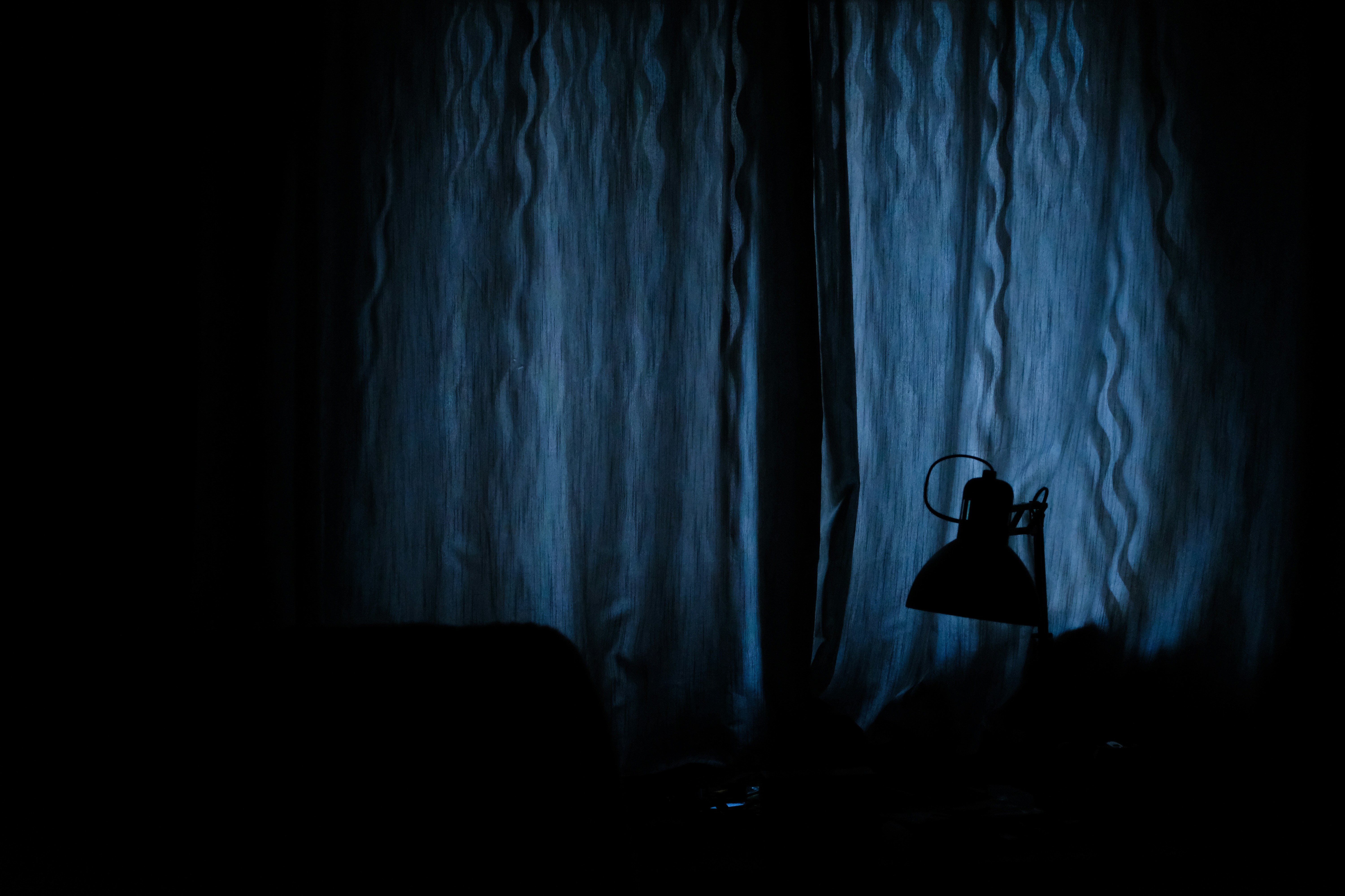 A person lying awake in a dark bedroom at night, staring pensively at the ceiling with a look of longing and insomnia, illuminated by soft moonlight.