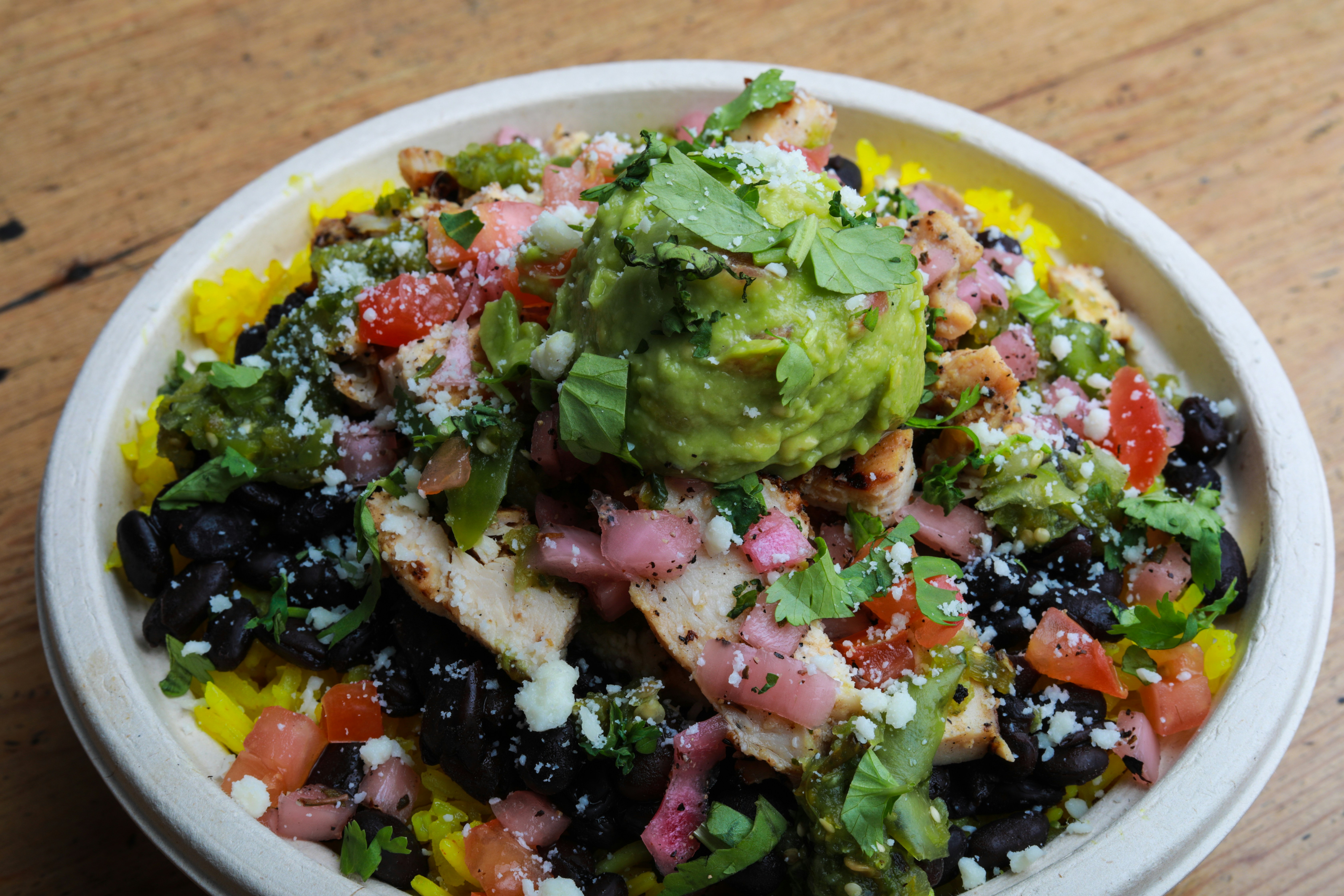 A colorful burrito bowl with a base of cauliflower rice, topped with seasoned ground turkey, black beans, salsa, and avocado