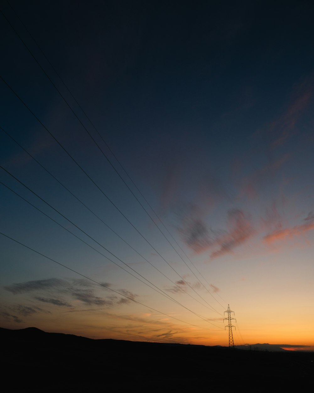 the sun is setting over a field with power lines