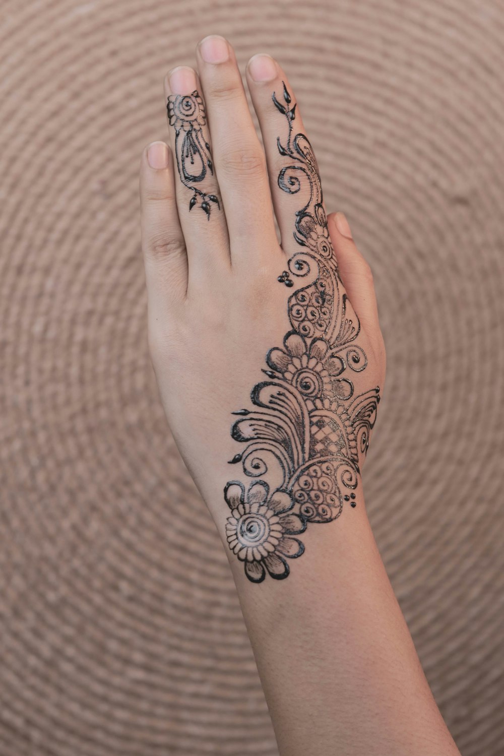 person showing left hand mendhi tattoo