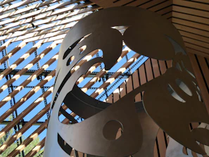 Metal art installation displayed outdoors, catching sunlight on its sharp contours.
