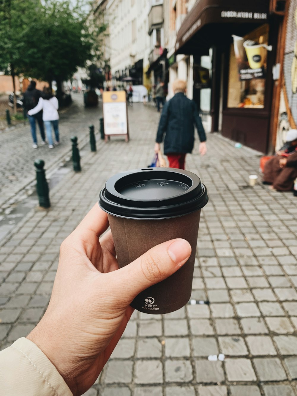 person holding brown and black coffee cup