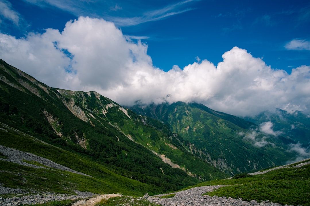 green covered mountain under white and blue skies during daytime