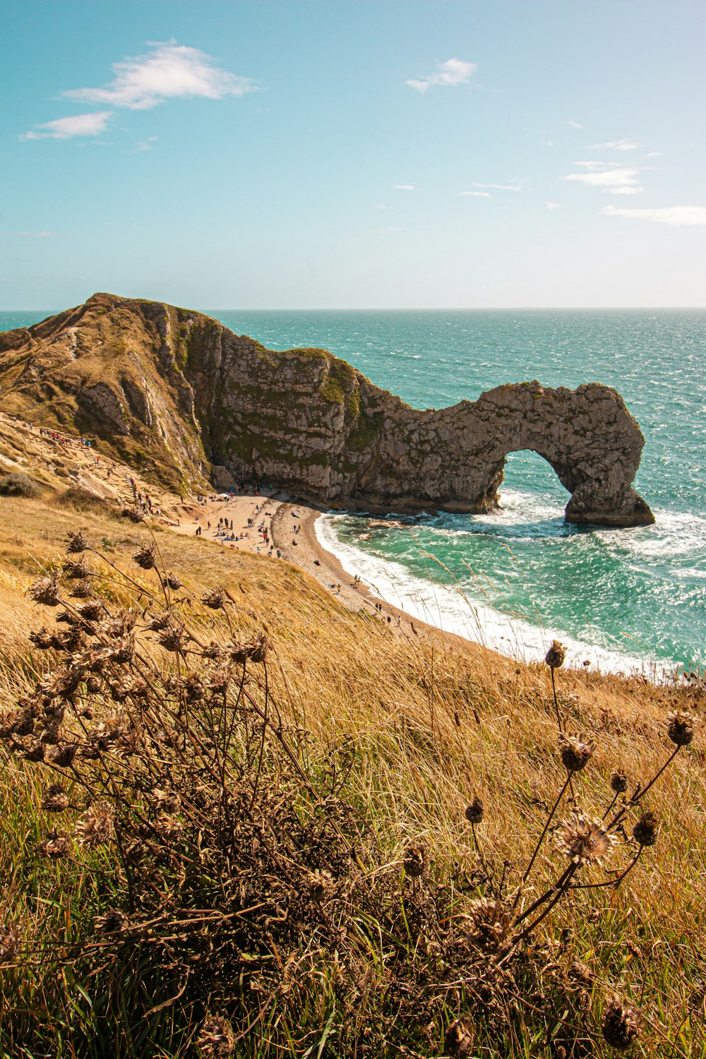 brown sand beach with arch rock