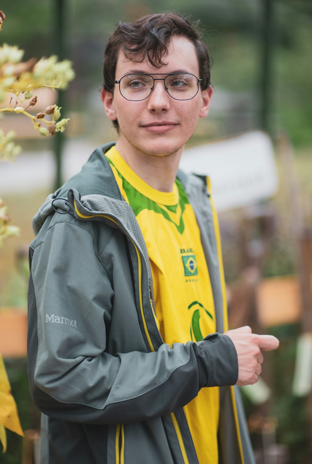 homem com camisa do Brasil e jaqueta cinza usando óculos