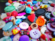 Colorful polyester buttons scattered on a fabric background.