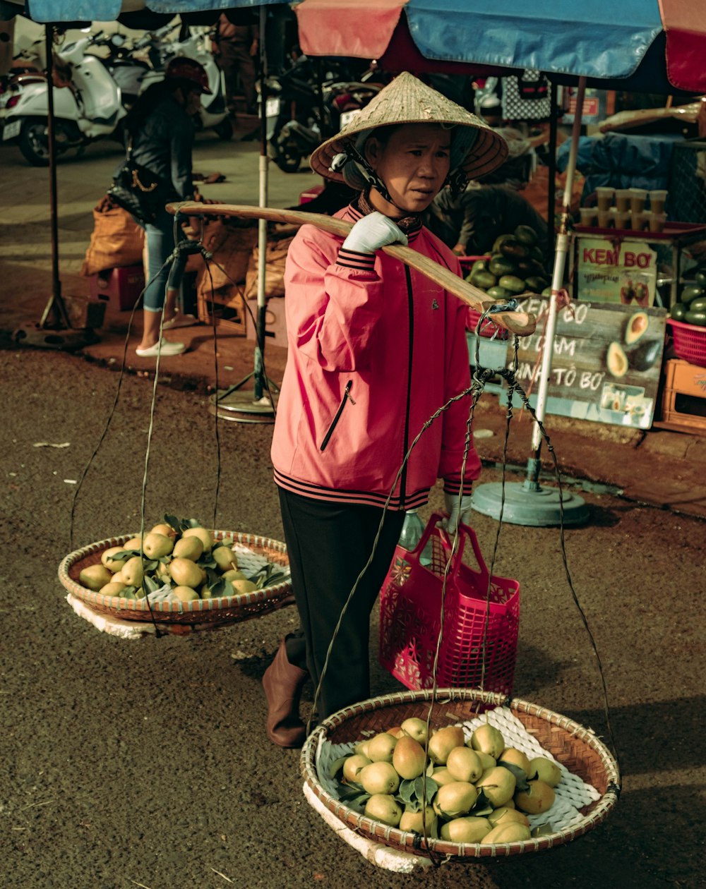 woman carrying two baskets of fruits