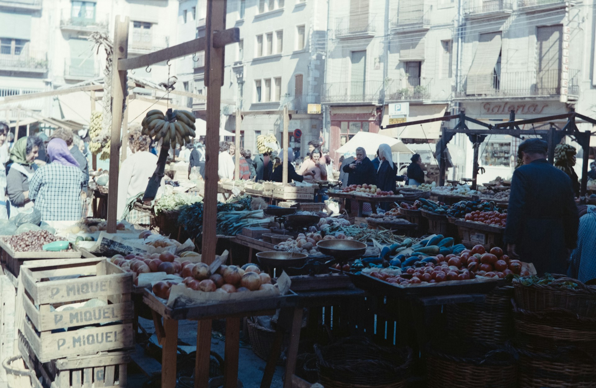 An old-fashioned village market scene with locals chatting and shopping for fresh produce.